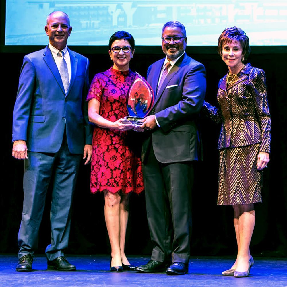 A group of people standing on a stage holding a trophy.