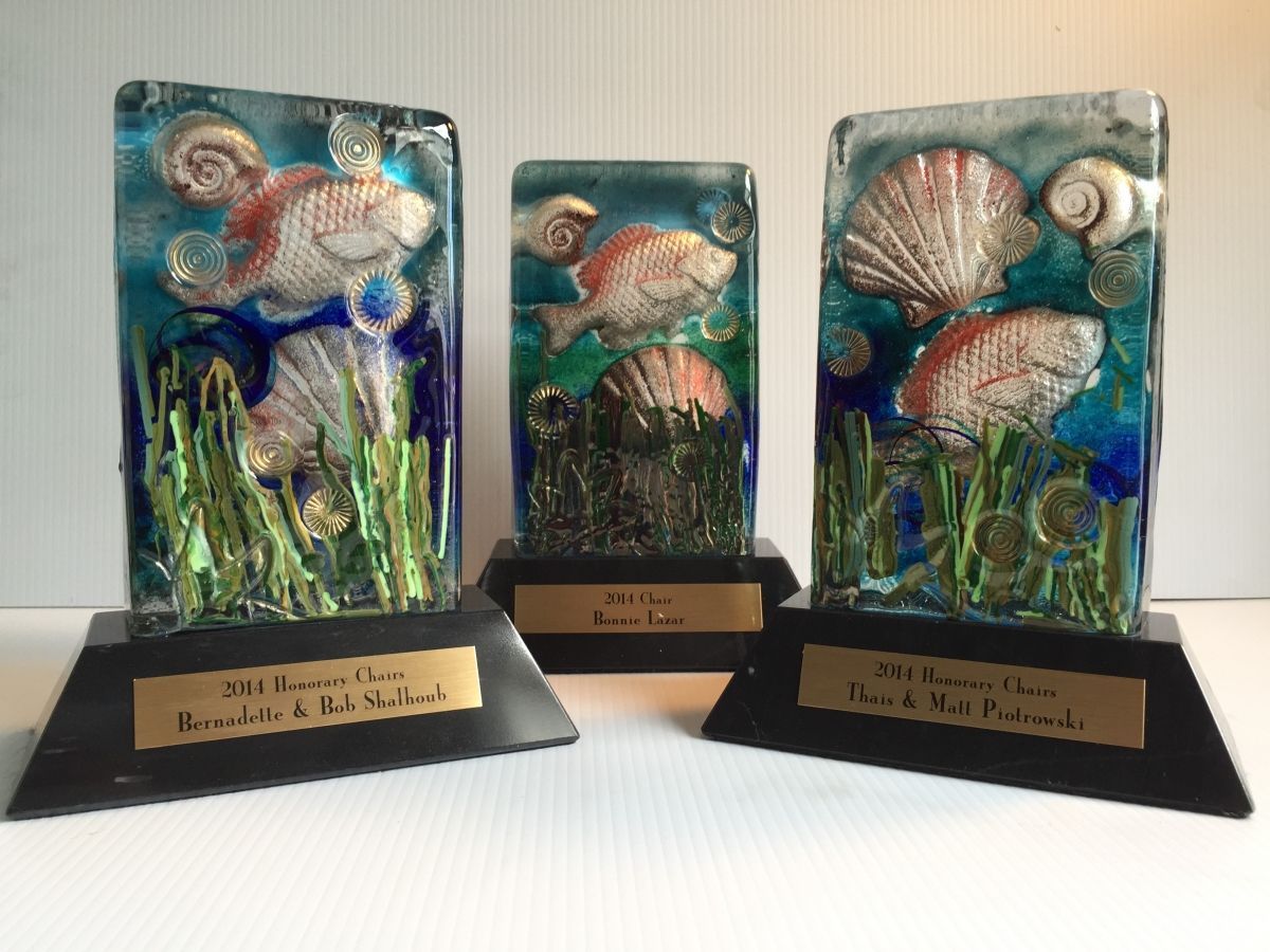 Three glass trophies with seashells and fish on them