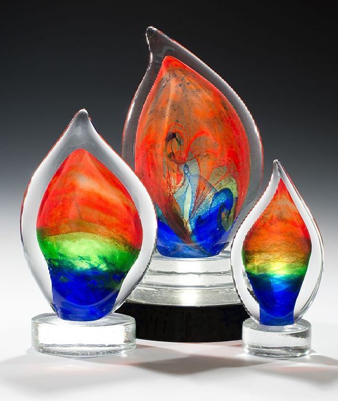 Three glass flame shaped trophies are sitting on a table