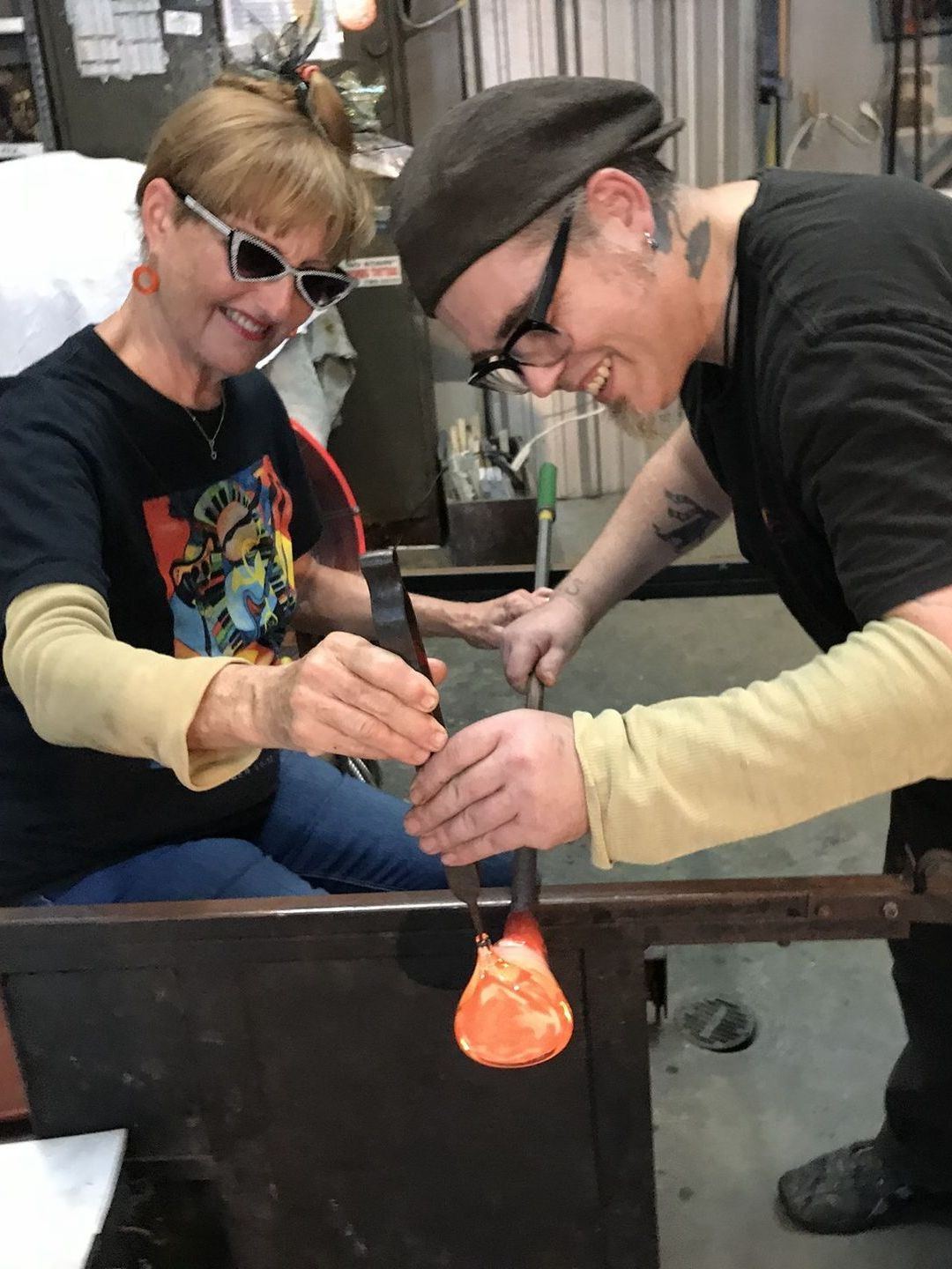 A man and a woman are working on a piece of glass.