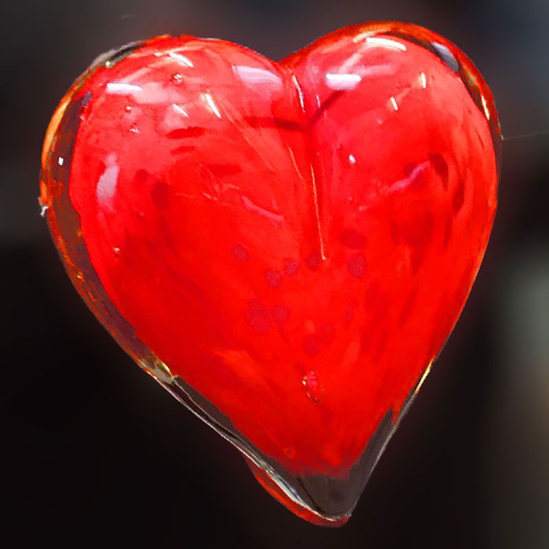 A close up of a red glass heart on a black background