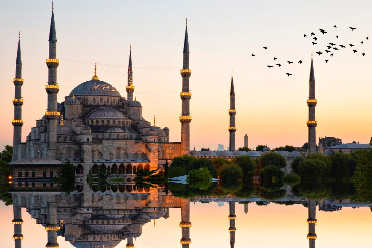 The blue mosque is reflected in the water at sunset.