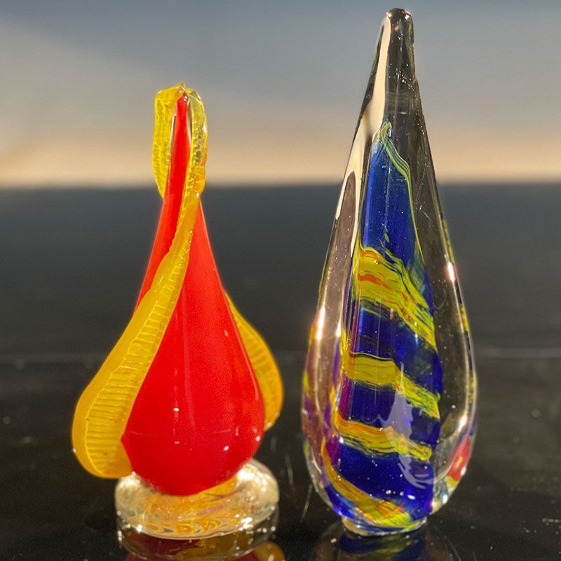A red and yellow glass sculpture next to a blue and yellow glass sculpture