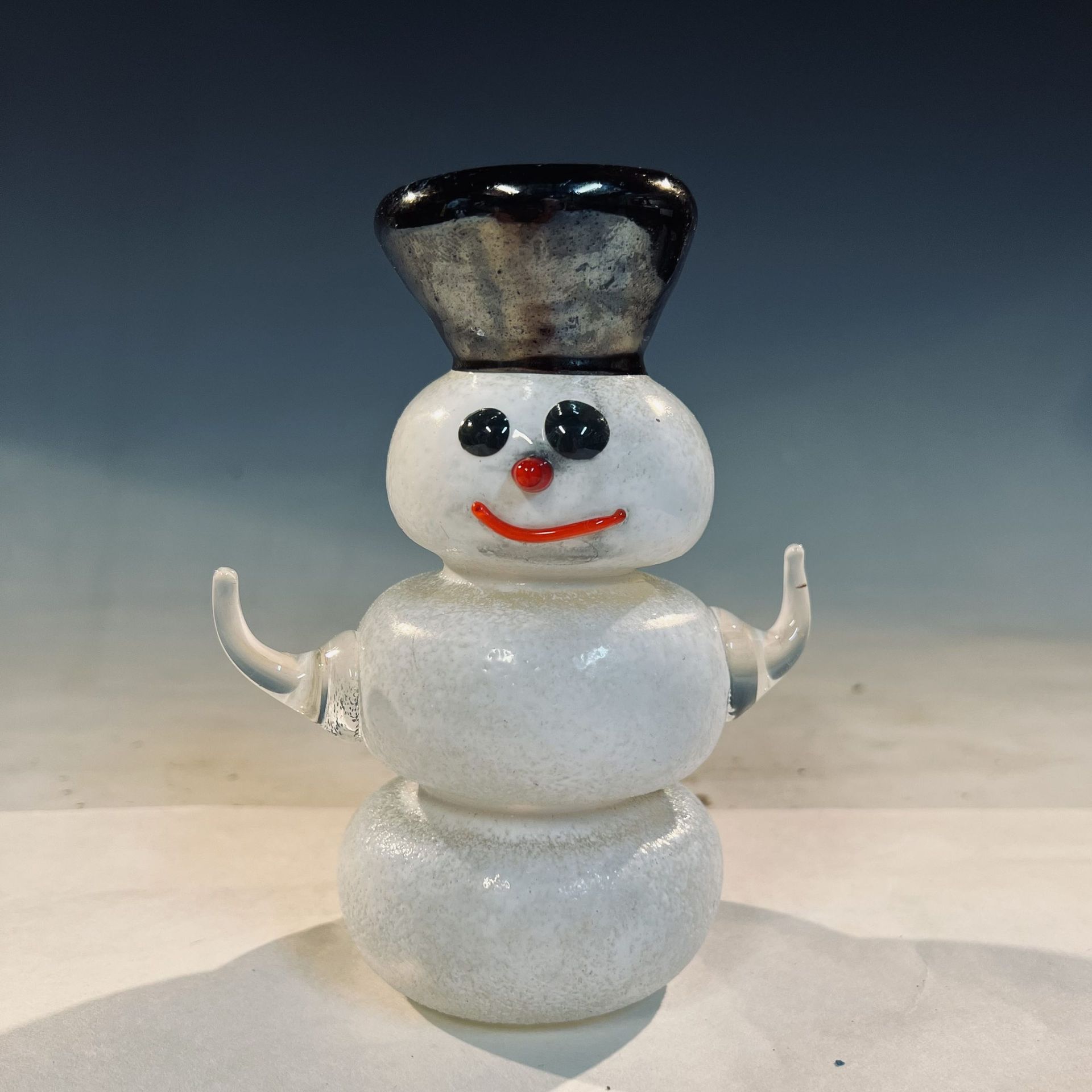 A glass snowman with a black hat on his head