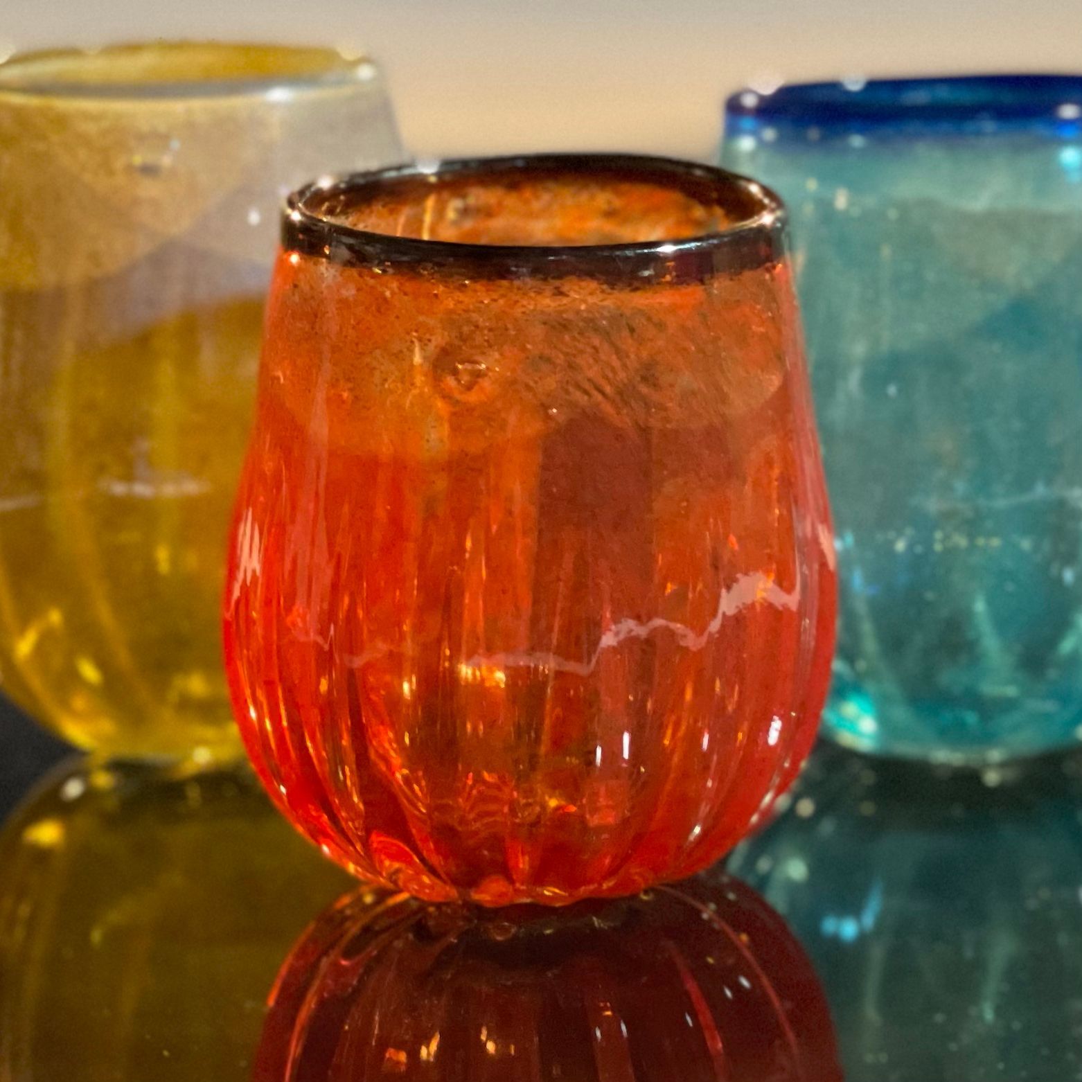 Three different colored glasses are sitting on a table