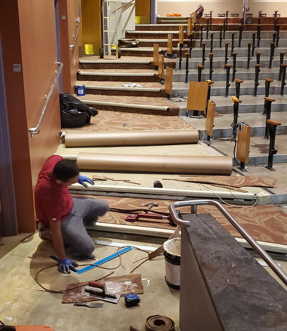 A carpet installation contractor finishes the flooring installation in this movie theater.