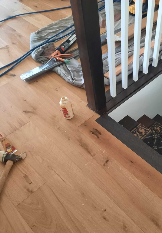 Hardwood flooring installation being finished in an upstairs room.