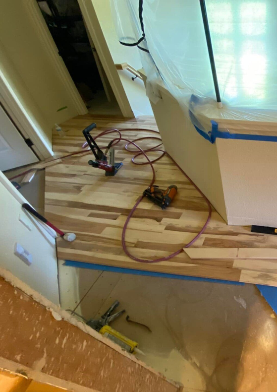 Working on hardwood flooring installation in a residential setting.