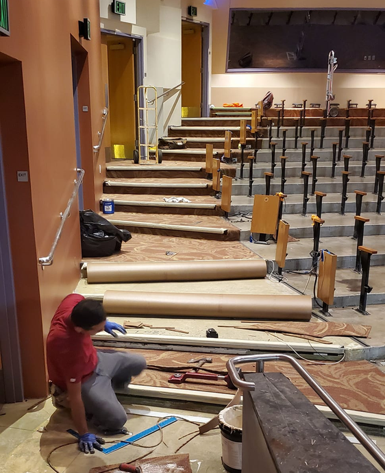 Carpet intstaller works on carpet flooring installation in a theater