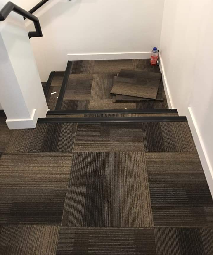 Carpet tile being installed on a set of stairs.