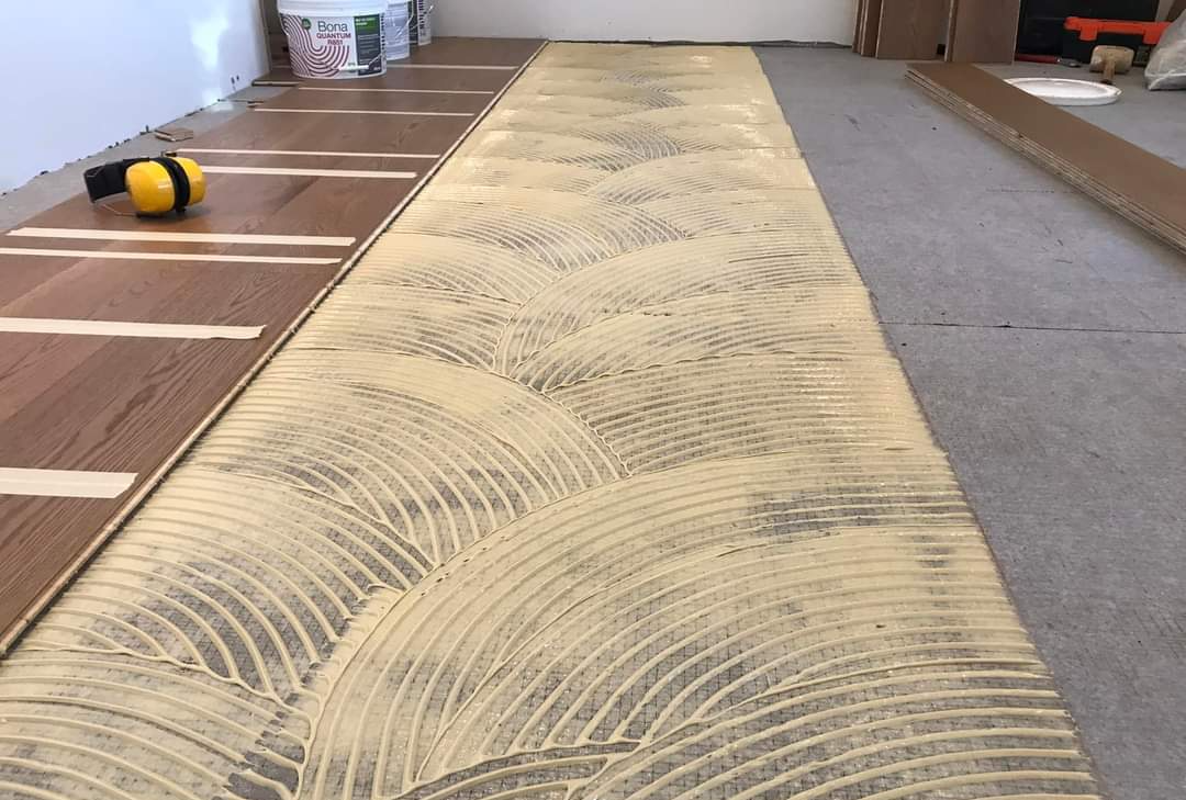 Adhesive is laid out on the floor for this glue down hardwood flooring install.