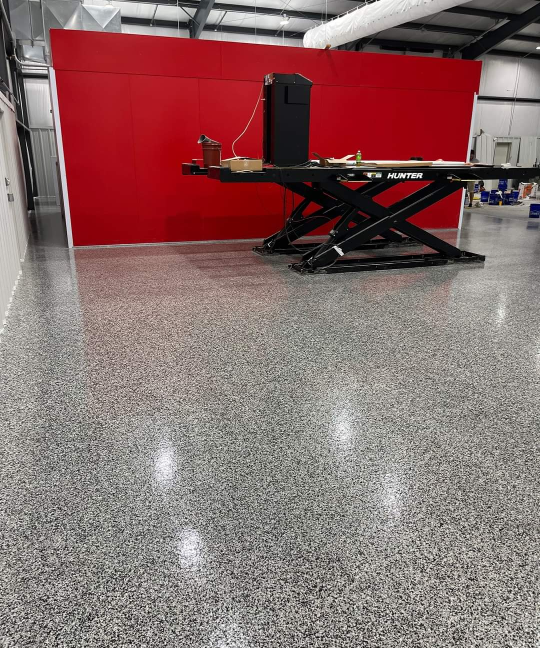 A scissor lift sits in the back of this garage that has freshly installed epoxy floors.