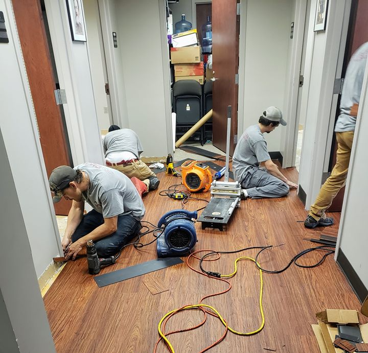 A team of flooring contractors working on the finer details of this LVP installation.