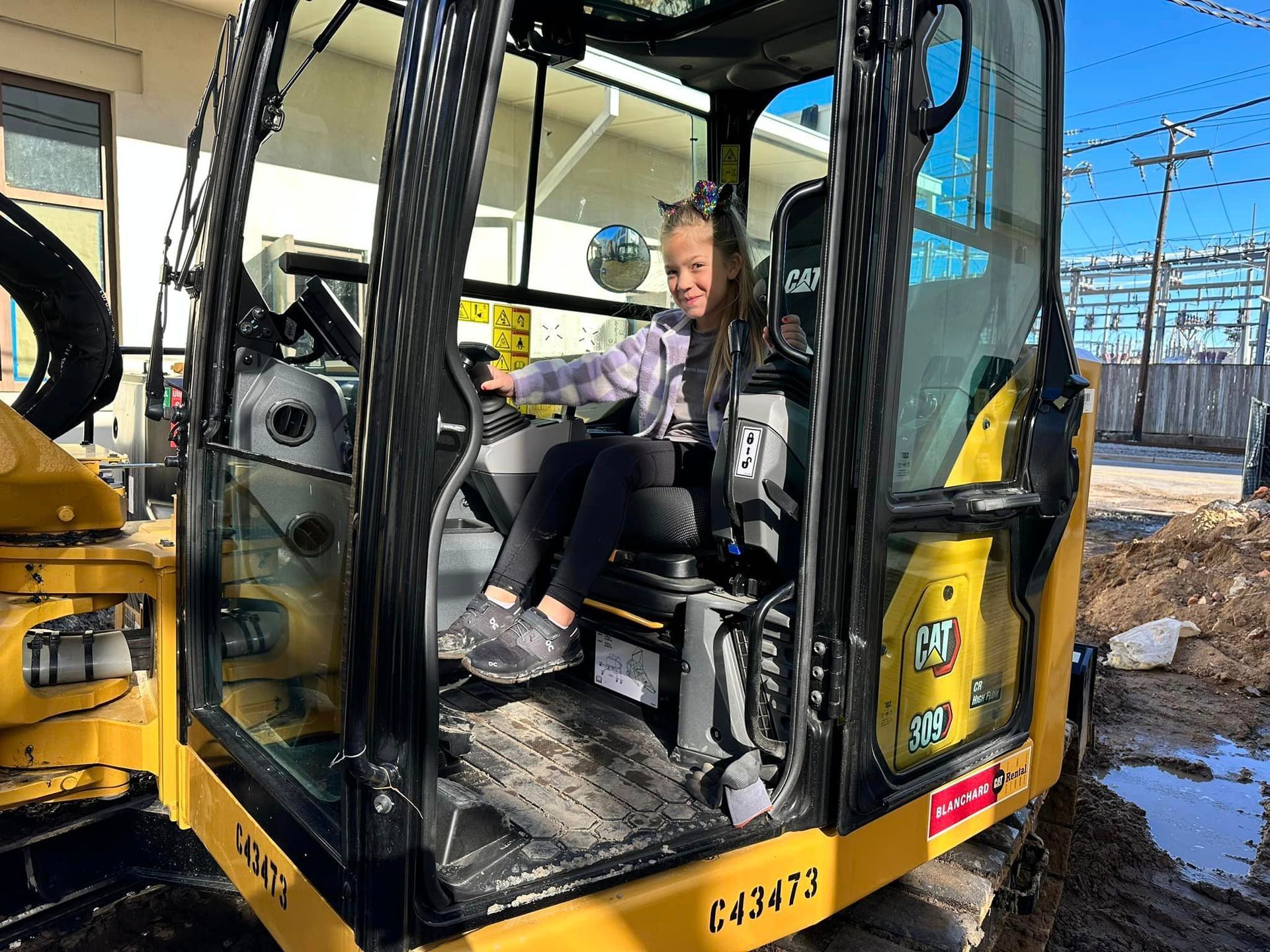 a girl is sitting in a yellow cat excavator