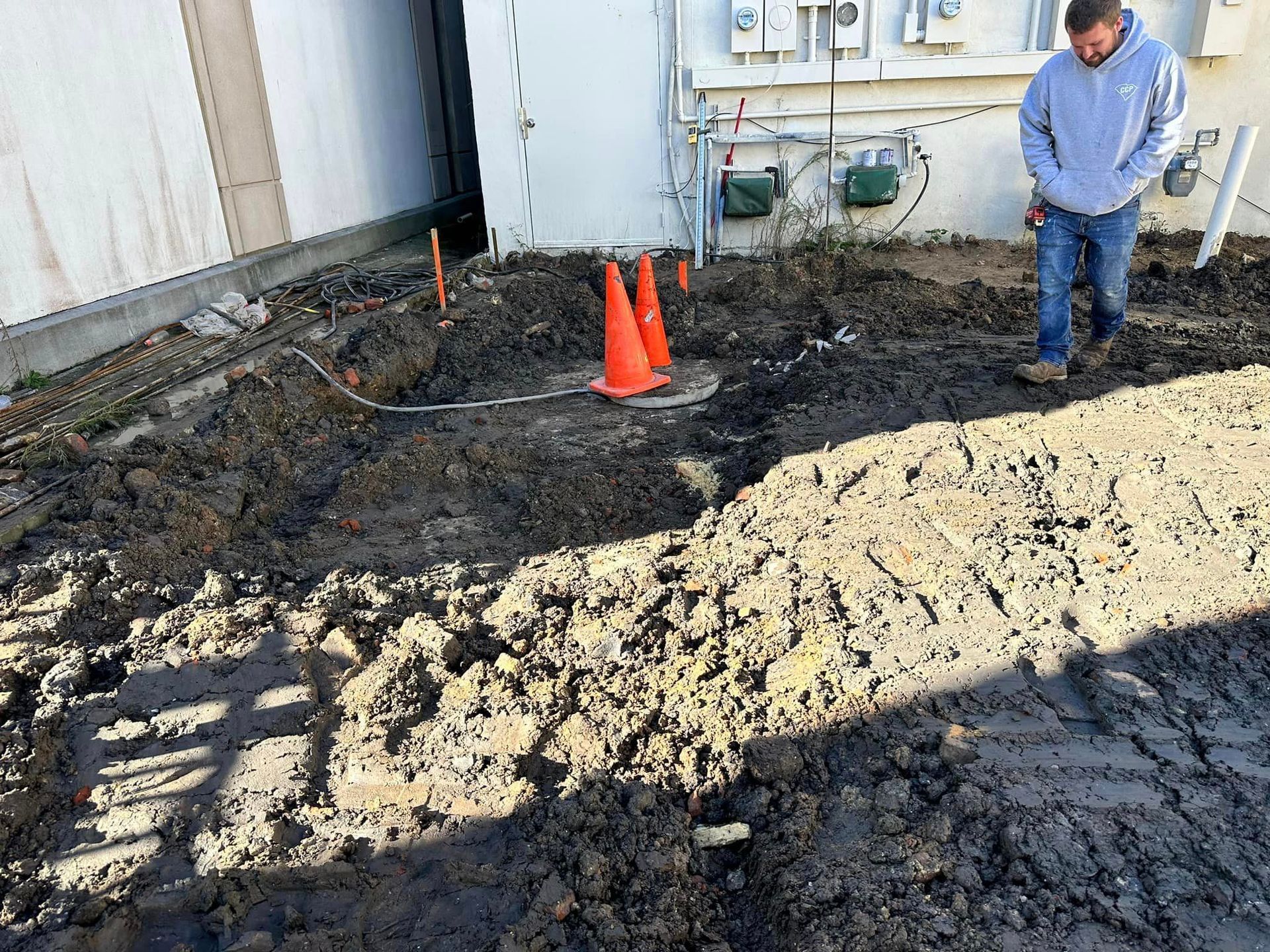 a man in a grey sweatshirt stands in a muddy area