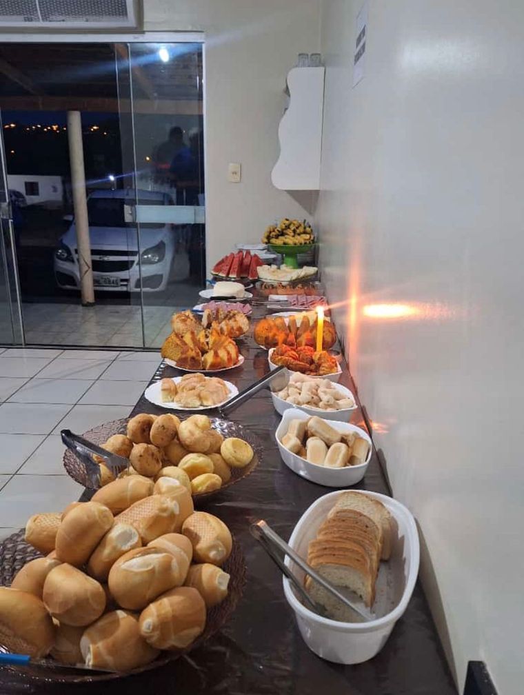 Uma mesa com muita comida e um carro ao fundo.