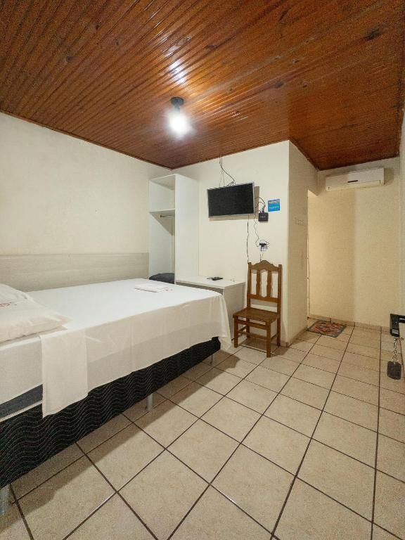 Um quarto de hotel com uma cama, uma cadeira e uma televisão