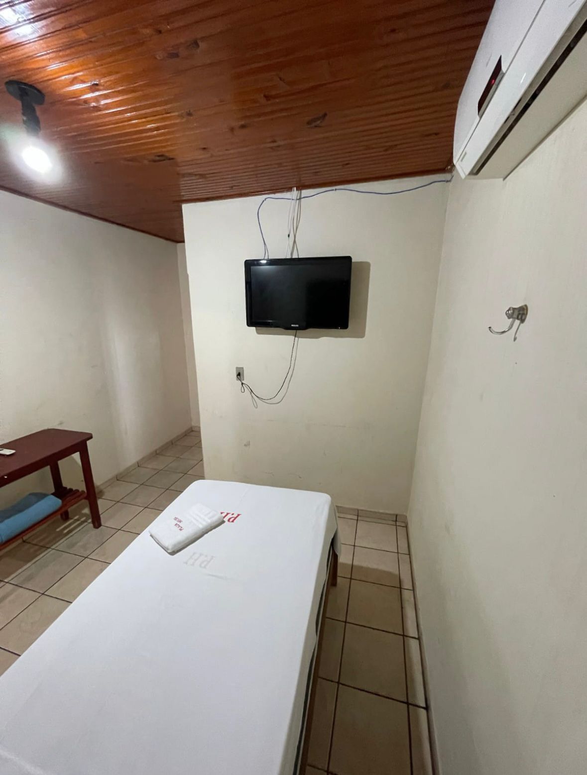 Um pequeno quarto com uma cama e uma televisão na parede.