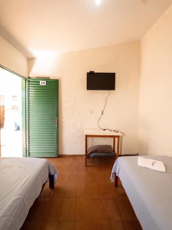 Um quarto de hotel com duas camas e uma televisão na parede.