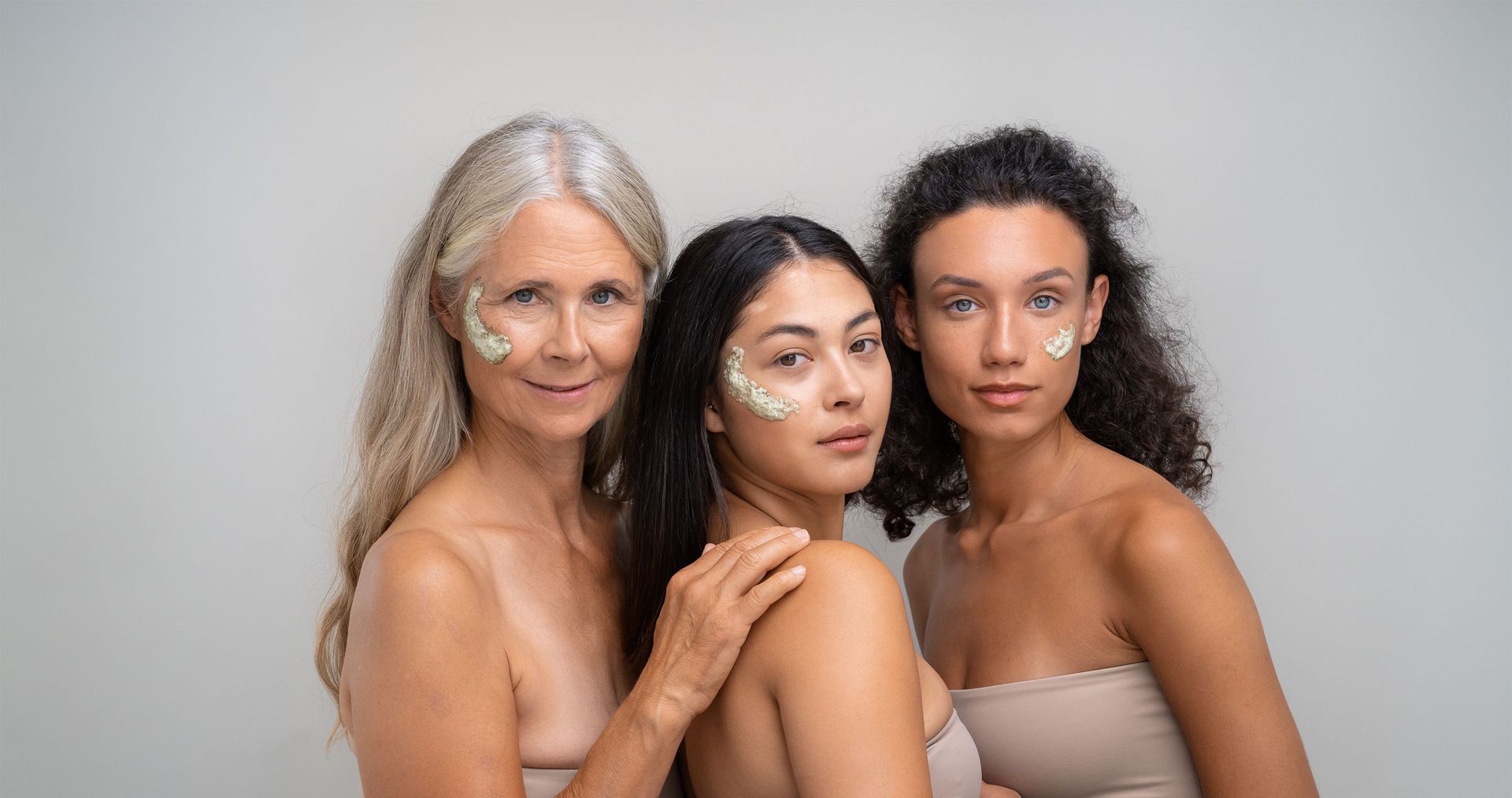 Three women with green peel on their faces are posing for a picture.