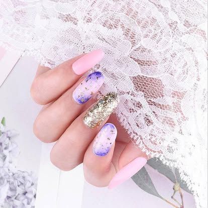 A close up of a woman 's nails with a purple and gold design.