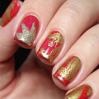 A woman 's nails are painted red and gold with a dragon design