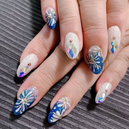 A close up of a woman 's nails with blue and white designs