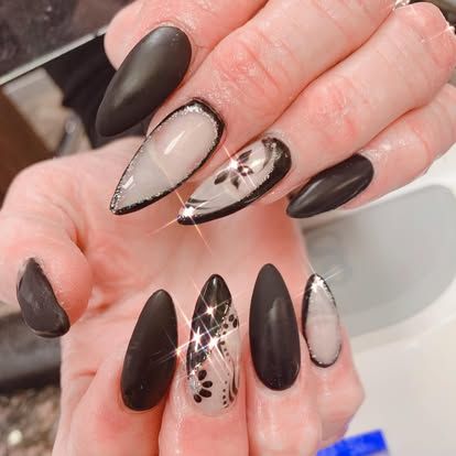 A close up of a woman 's hand with long black nails.