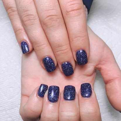 A close up of a woman 's hand with blue nails