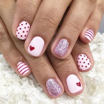 A close up of a person 's nails with polka dots and a heart on them.