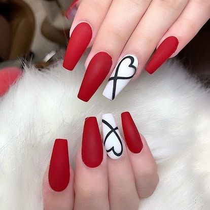 A woman 's nails are red and white with a heart design.