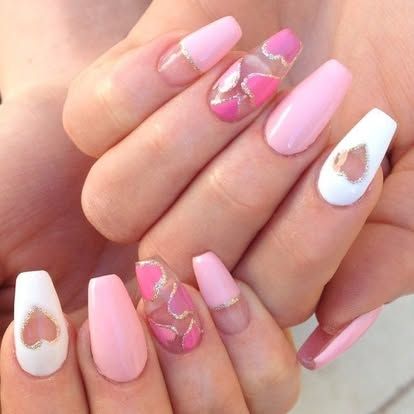 A close up of a woman 's pink and white nails with hearts on them