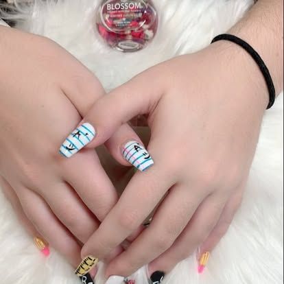 A close up of a person 's hands with a bottle of blossom nail polish in the background.