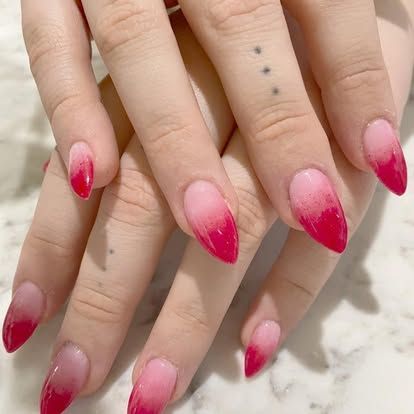 A close up of a woman 's nails with a red ombre design.