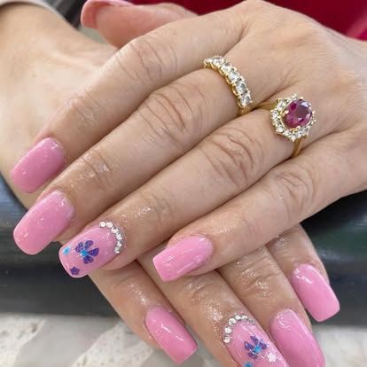 A close up of a woman 's hand with pink nails and two rings