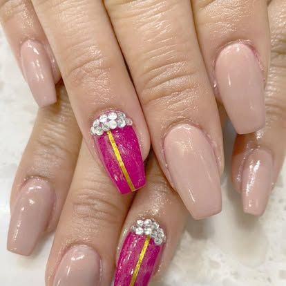 A close up of a woman 's nails with a pink and gold design.