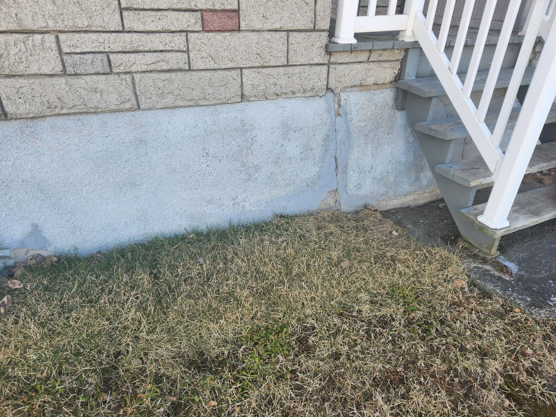 Un mur de briques avec des escaliers qui y mènent et une balustrade blanche.