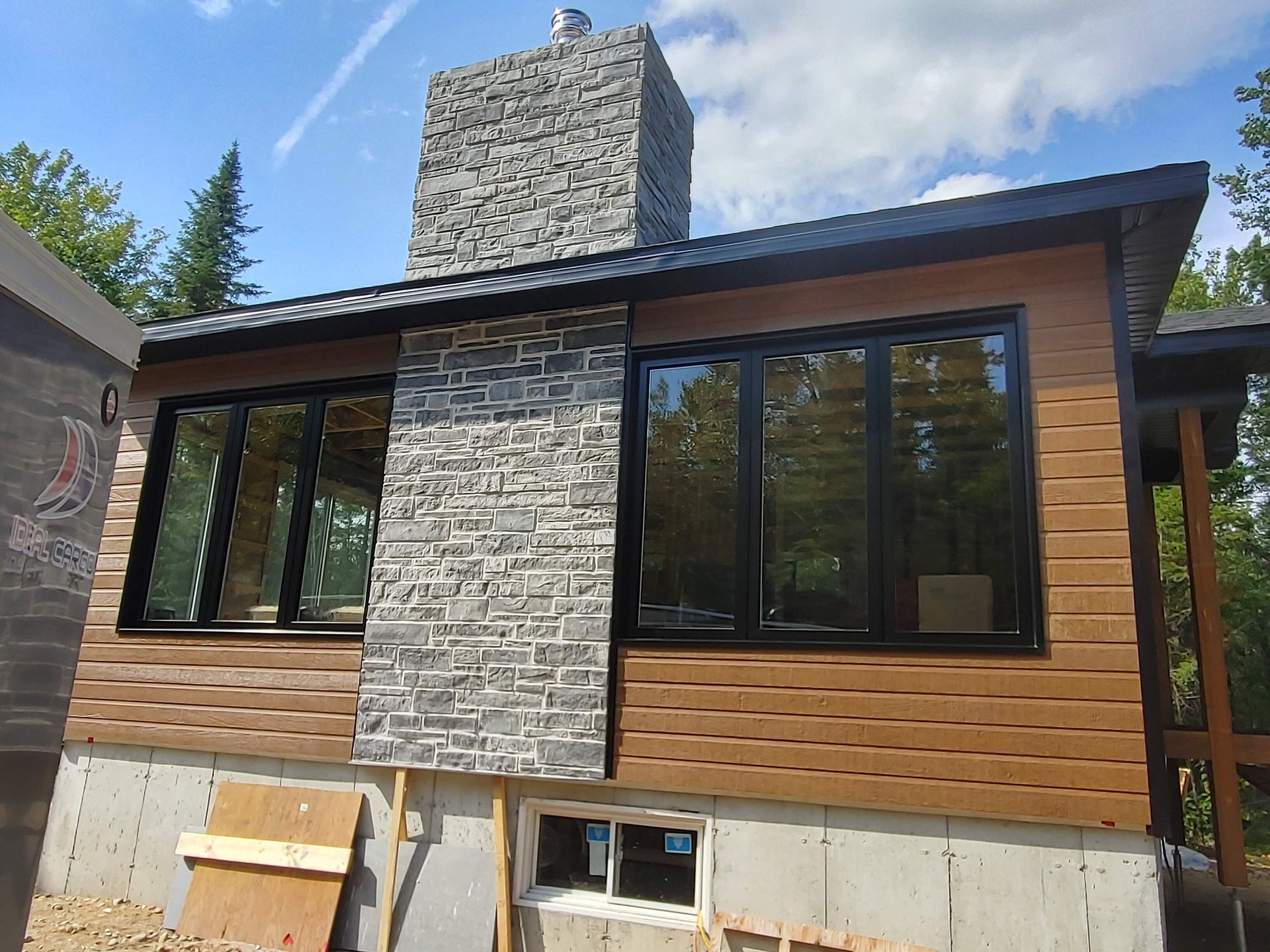 Une maison avec une cheminée et beaucoup de fenêtres est en construction.