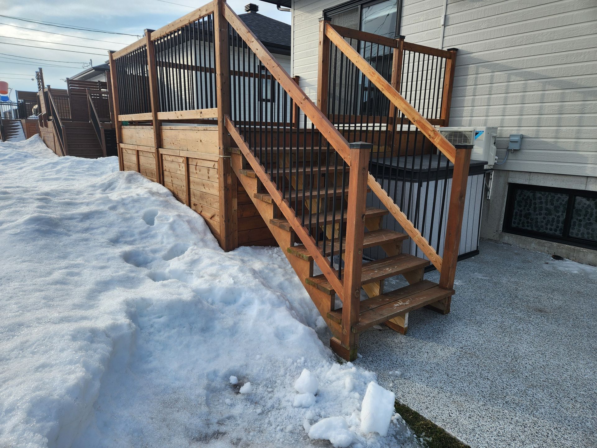 Une terrasse en bois avec des escaliers menant à celle-ci dans la neige.