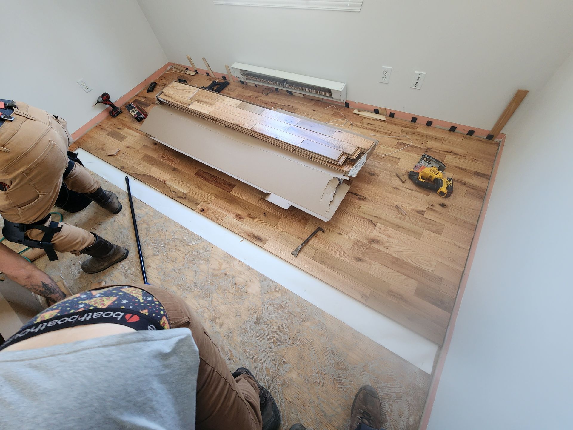 Une personne se tient debout sur un plancher en bois dans une pièce.