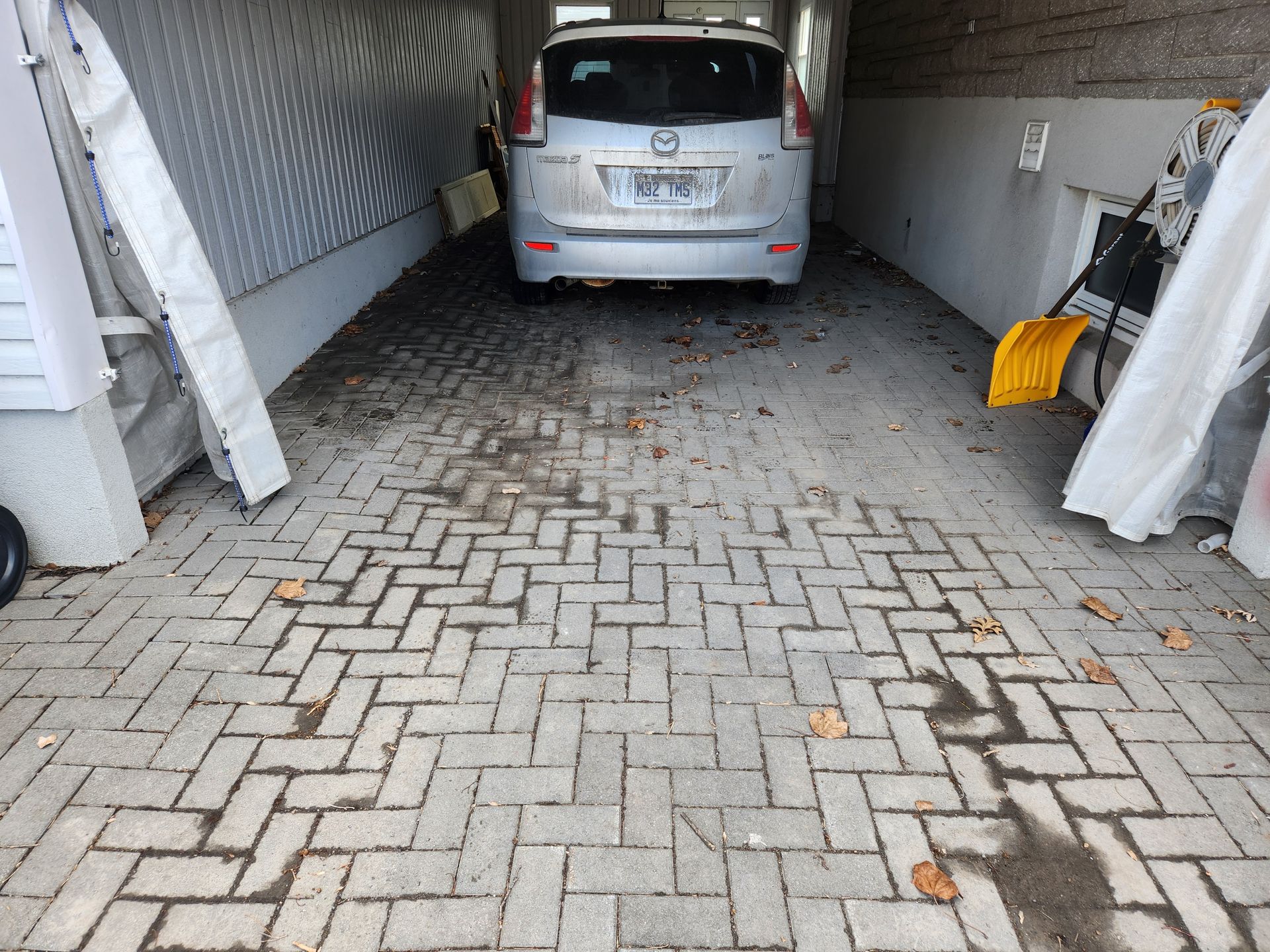 Une voiture argentée est garée dans une allée en briques