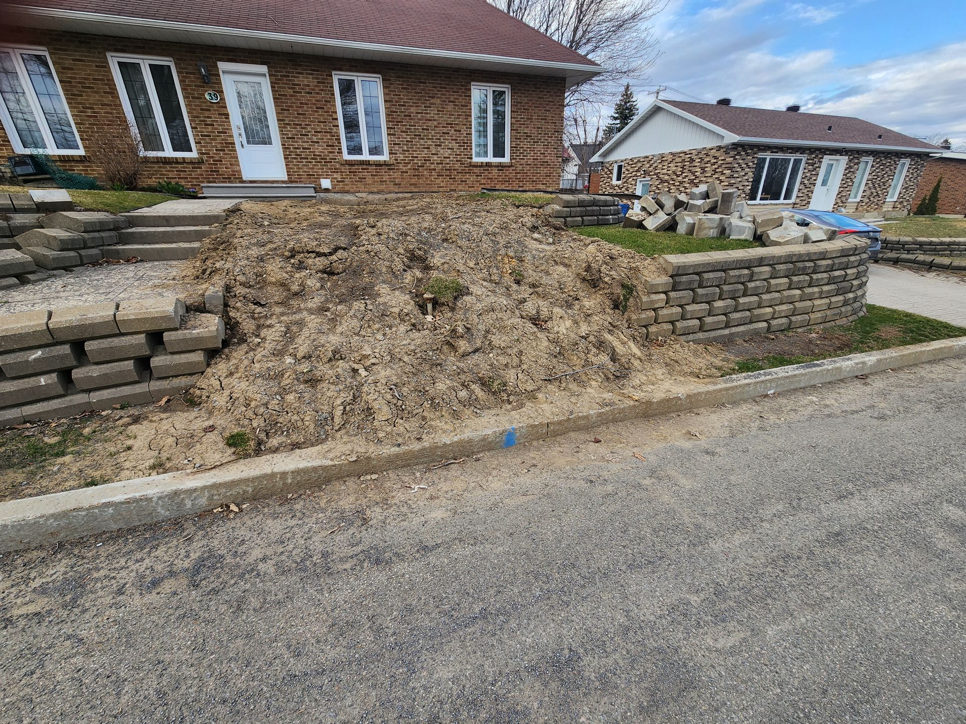 Une maison en briques avec un mur en pierre devant.