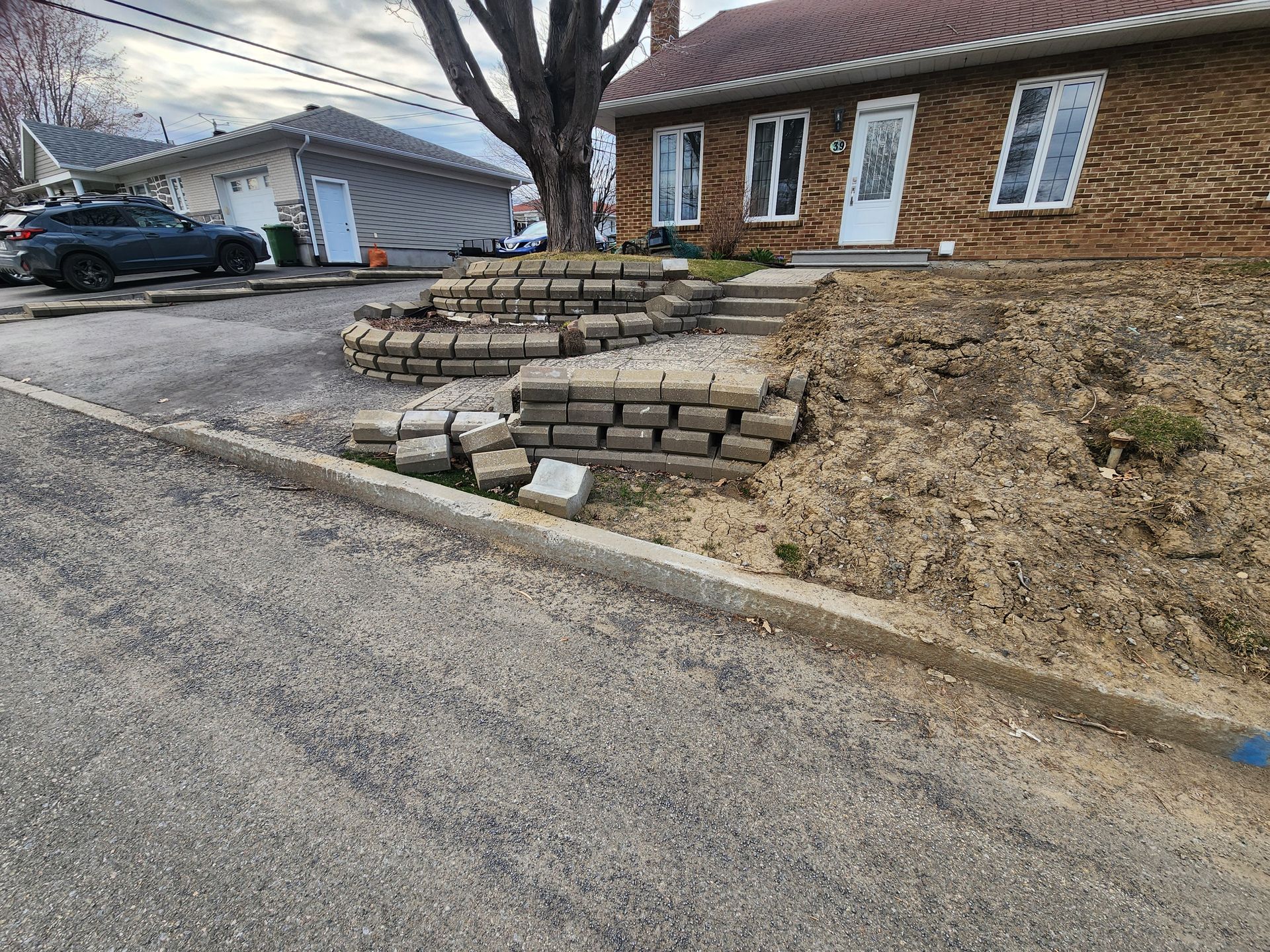 Un mur de pierre est en train d'être construit devant une maison.