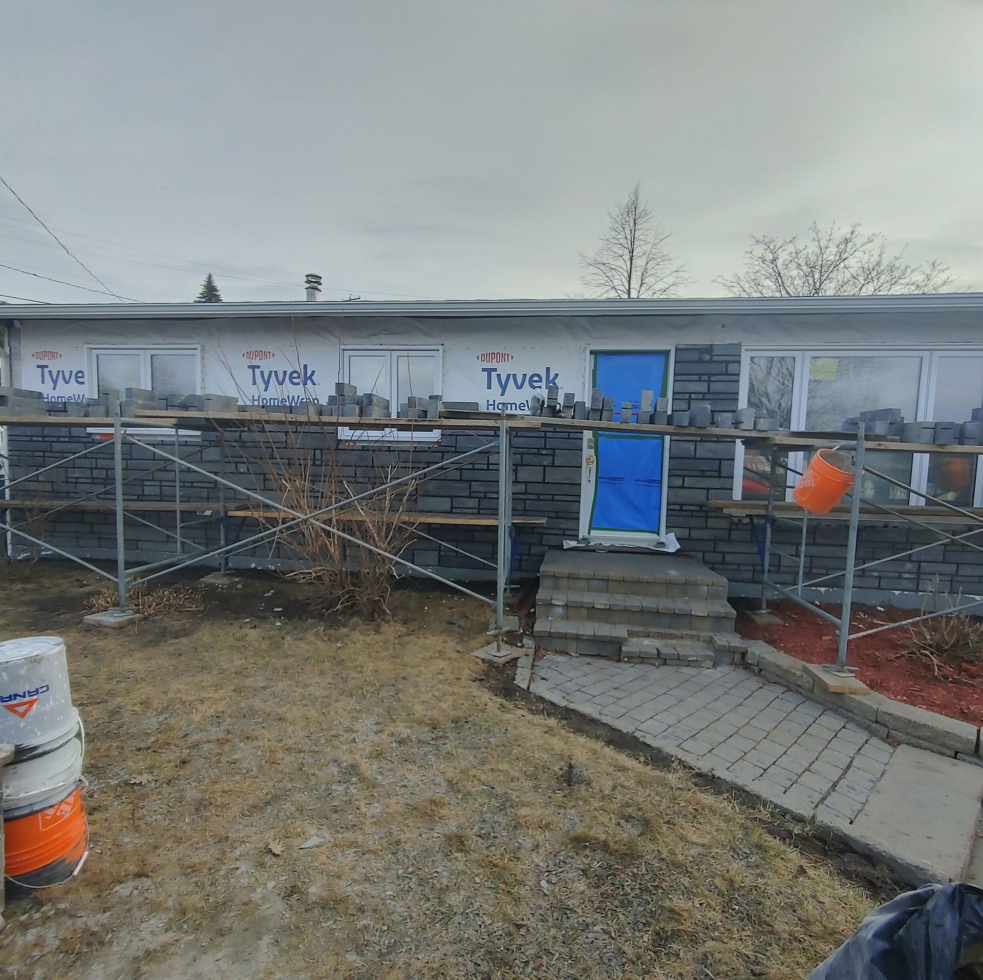 Une maison est en construction avec des briques et une porte bleue.