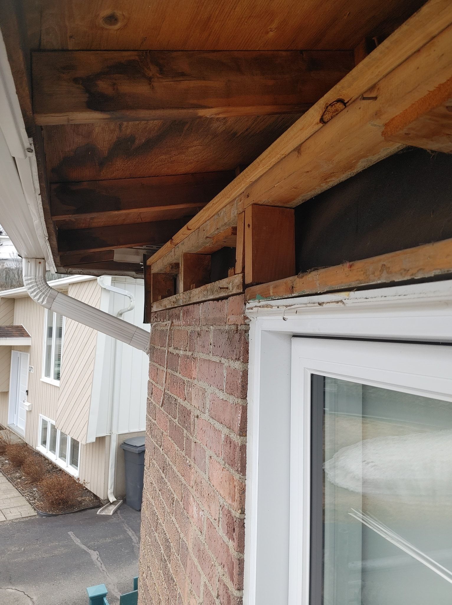 Un bâtiment en briques avec une fenêtre blanche et un toit en bois.