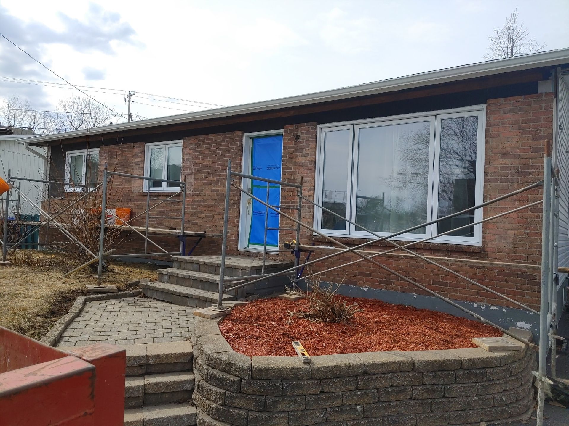 Une maison en briques avec une porte bleue est en cours de rénovation.