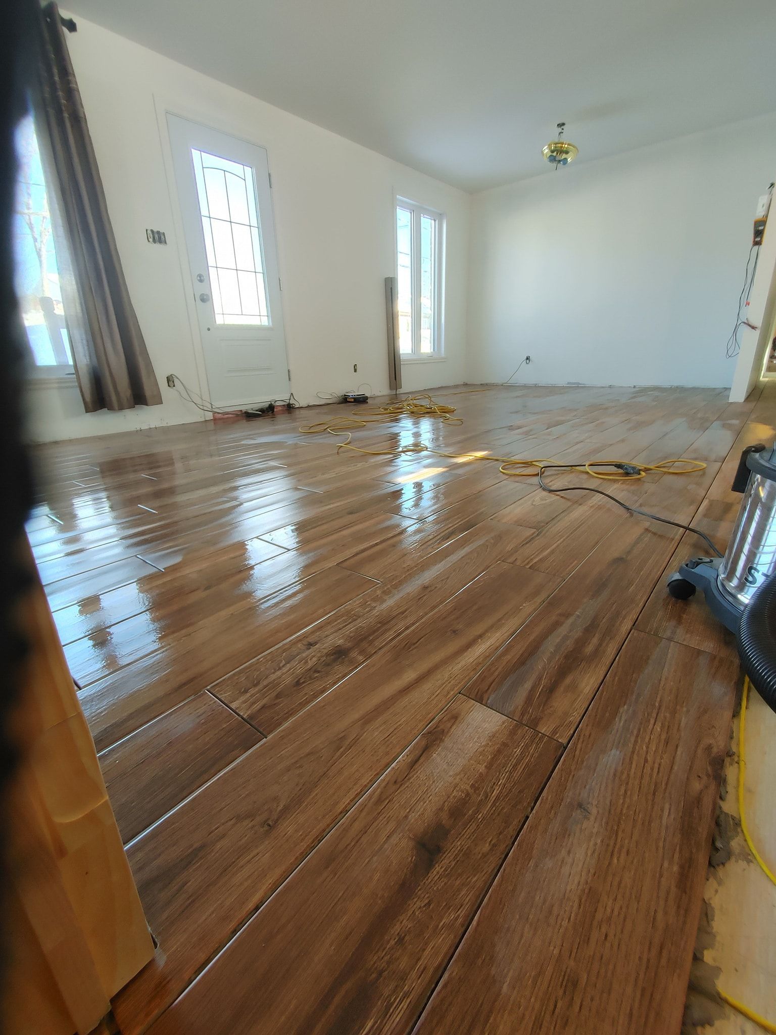 Un salon avec parquet et murs blancs.