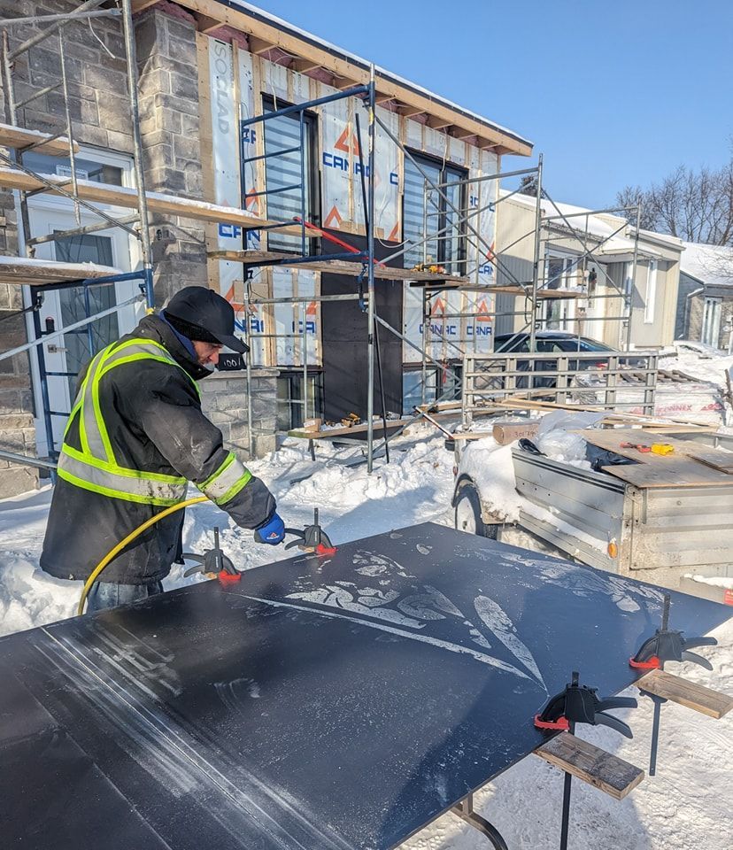Un homme travaille sur un morceau de bois dans la neige.