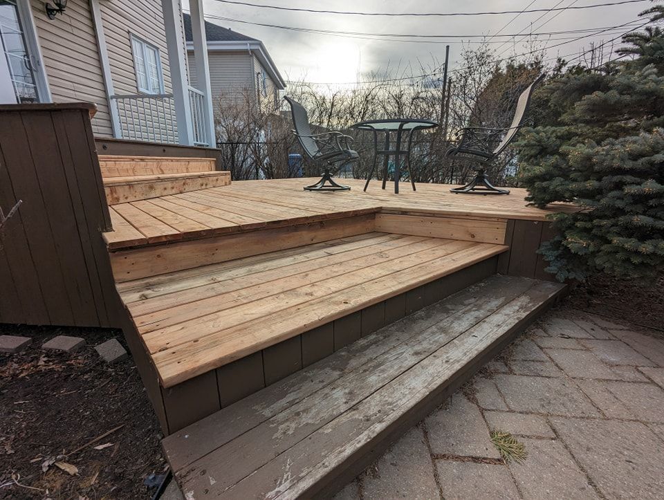 Une terrasse en bois avec des escaliers et une table et des chaises dessus.