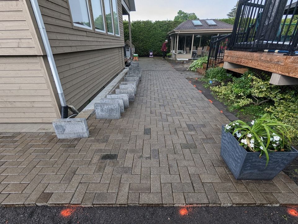 Une allée en briques menant à une maison avec une jardinière devant.